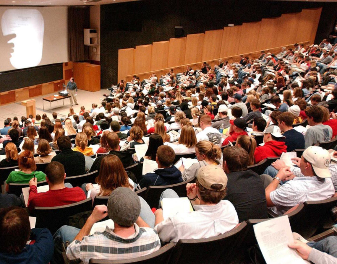 A group of people sitting at a table in front of a crowd

Description automatically generated