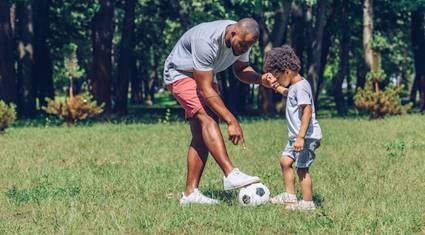 A person and a child playing with a football ball

Description automatically generated with medium confidence