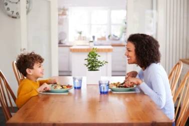 A person and a child eating at a table

Description automatically generated